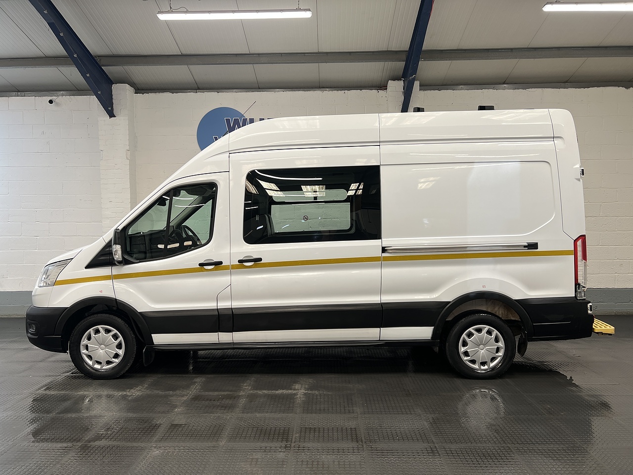 Side profile of a white Ford Transit L3 welfare van with yellow safety stripe